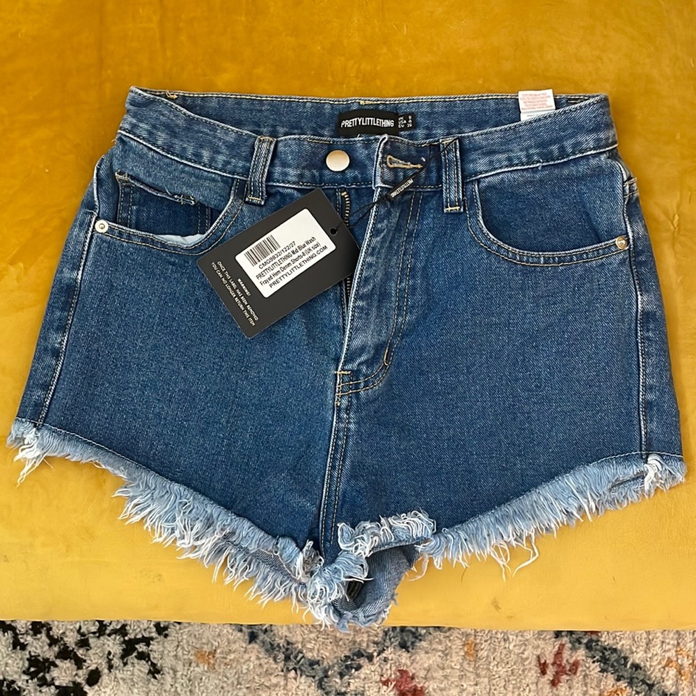 High rise jean shorts with frayed edge. Medium wash. Never worn with tag